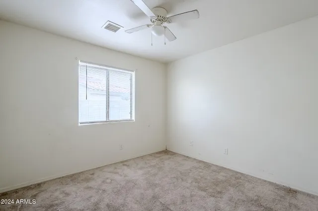an empty room with windows and fan
