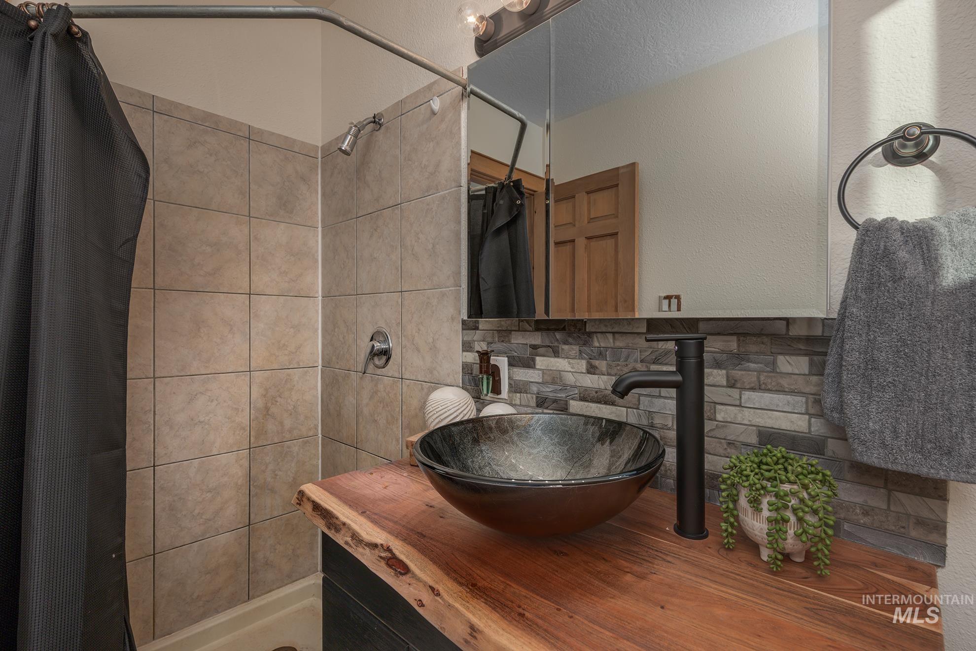 1855 Jones Road Weiser, ID 83672 - Photo 16 of 34 Bathroom with a shower stall, vanity, a textured wall, and tasteful backsplash
