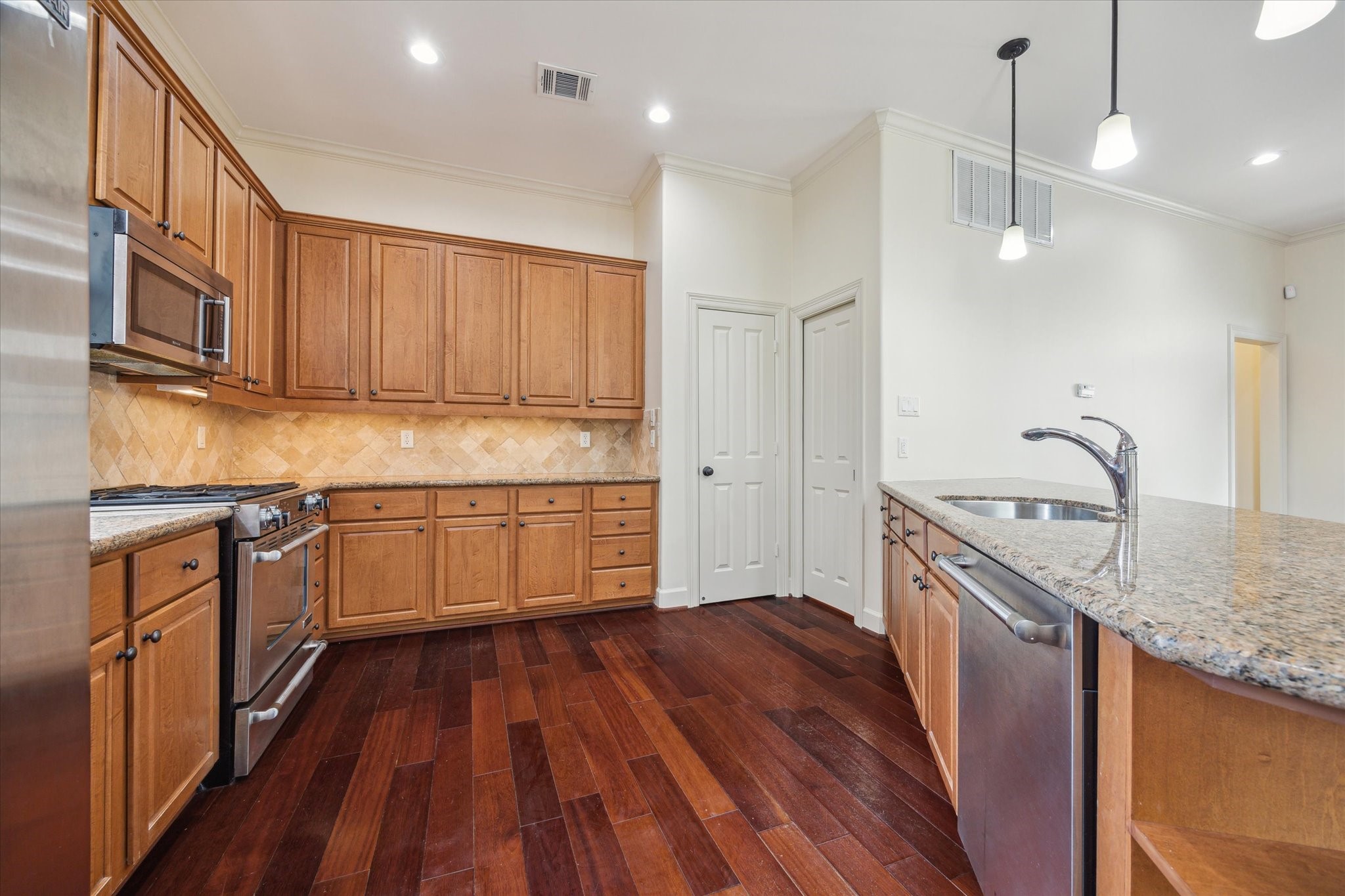 415 Tuam Street Houston, TX 77006 - Photo 7 of 21 a kitchen with granite countertop wooden floors appliances and cabinets