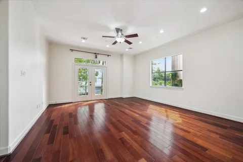 a view of an empty room with wooden floor and a ceiling fan