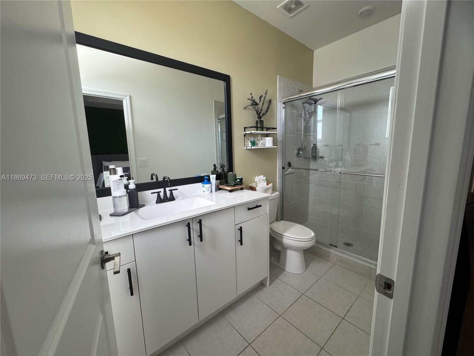 16270 Southwest 293rd Street Homestead, FL 33033 - Photo 10 of 13 a bathroom with a toilet a sink a mirror and a shower