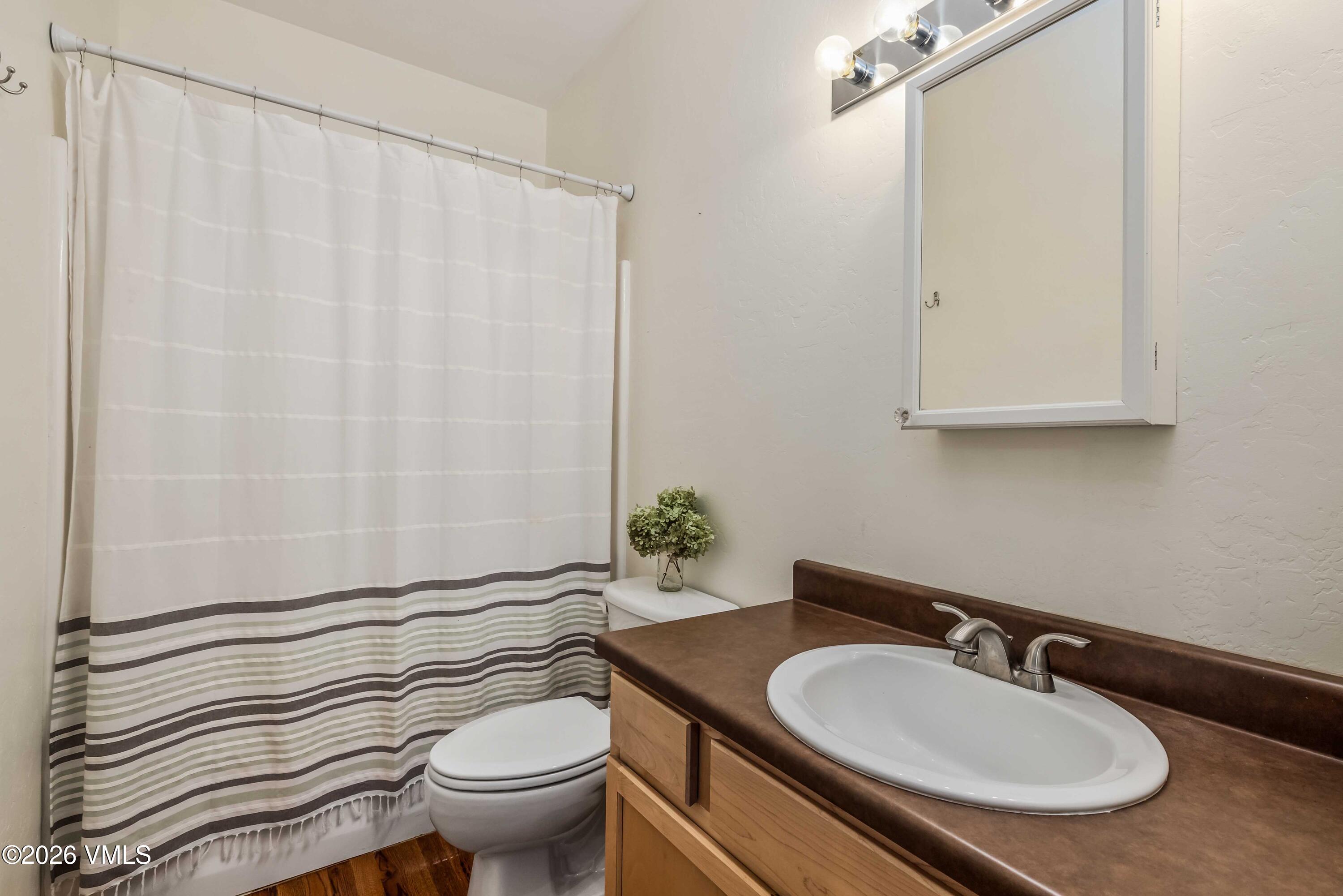 491 Metcalf Road, Unit A2 Avon, CO 81620 - Photo 16 of 23 a bathroom with a granite countertop sink a toilet and a mirror