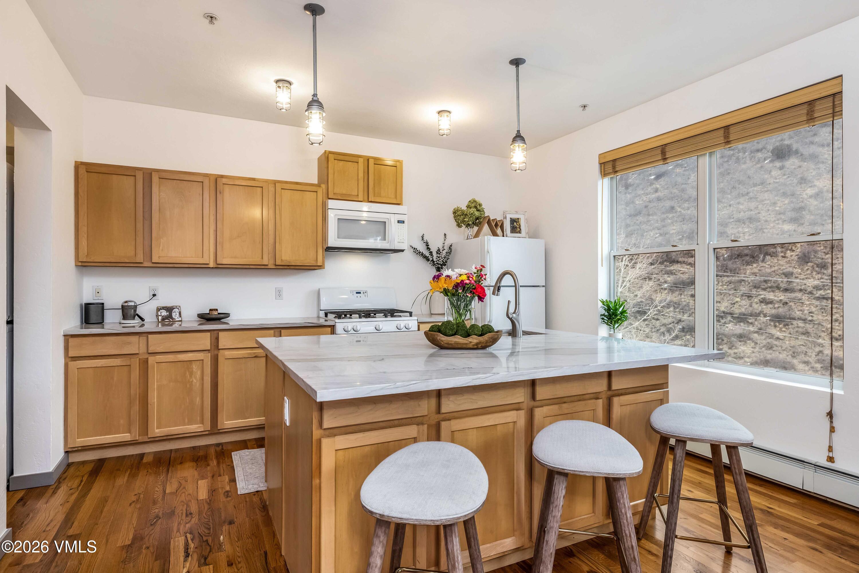 491 Metcalf Road, Unit A2 Avon, CO 81620 - Photo 3 of 23 a kitchen with stainless steel appliances granite countertop a sink a microwave a dining table and chairs with wooden floor