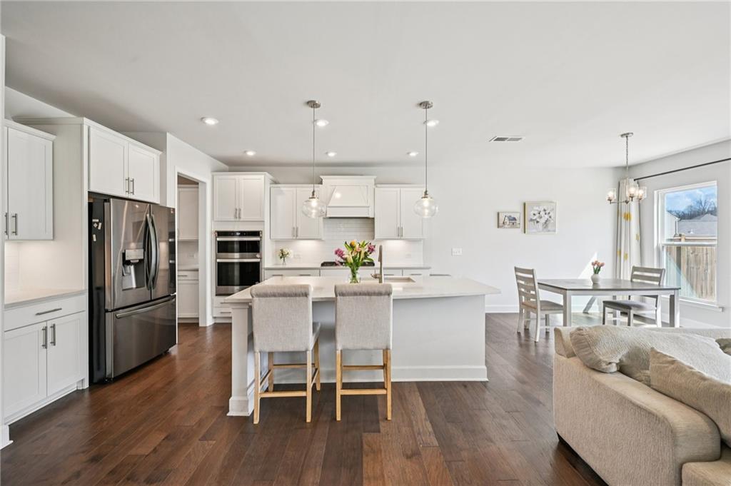 1283 Maston Road Auburn, GA 30011 - Photo 11 of 82 a kitchen with stainless steel appliances kitchen island granite countertop a dining table chairs refrigerator and sink