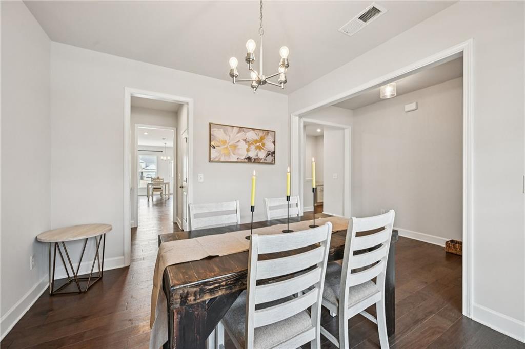 1283 Maston Road Auburn, GA 30011 - Photo 13 of 82 a dining room with wooden floor a chandelier a wooden table and chairs