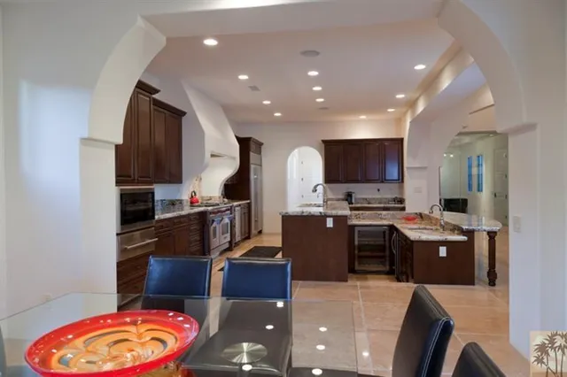 a kitchen with stainless steel appliances kitchen island granite countertop a sink dishwasher stove and refrigerator