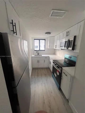 a kitchen with stainless steel appliances a refrigerator a sink a stove and cabinets