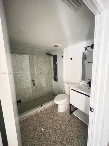 a bathroom with a granite countertop toilet a sink a shower and a mirror