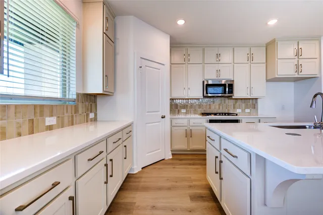 a kitchen with kitchen island white cabinets stainless steel appliances a sink and a window