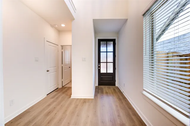 a view of a hallway with wooden floor and a window