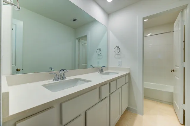 a bathroom with a sink double vanity granite tub shower and a mirror