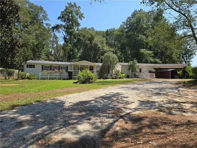 a view of house with yard and trees in the background