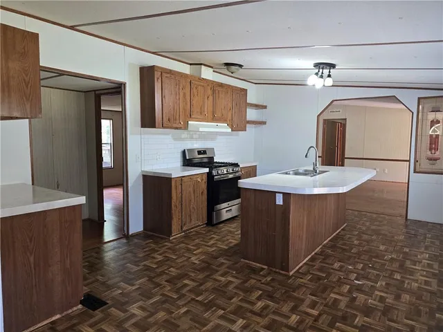 a kitchen with stainless steel appliances granite countertop a sink a stove a refrigerator cabinets and a dining table