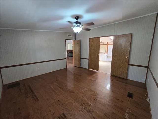 a view of a livingroom with wooden floor a ceiling fan and staircase