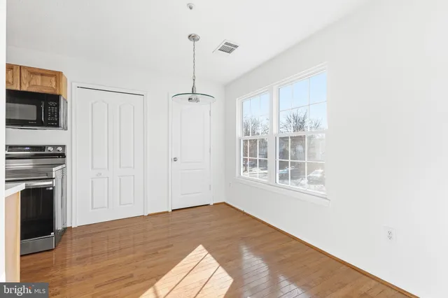a view of empty room with wooden floor and fan