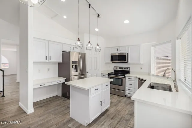 a kitchen that has a lot of white cabinets and stainless steel appliances