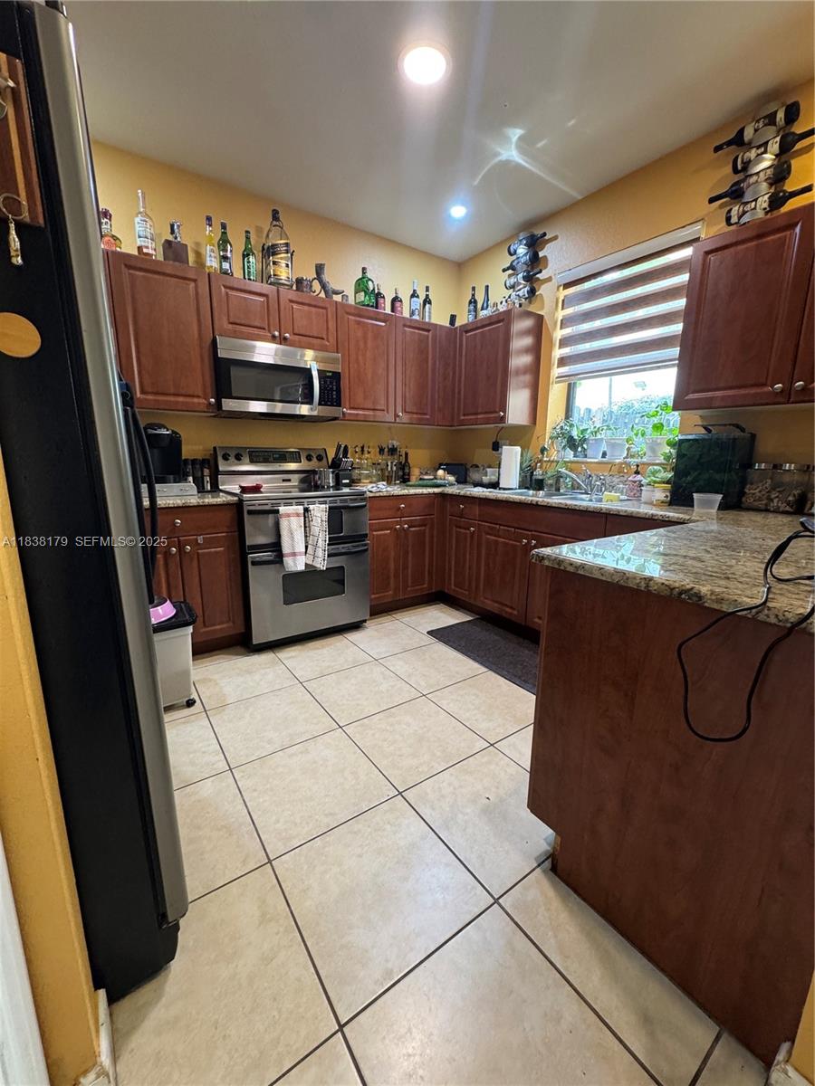 23477 Southwest 112th Place Homestead, FL 33032 - Photo 5 of 49 a kitchen with stainless steel appliances granite countertop a stove a sink and a microwave