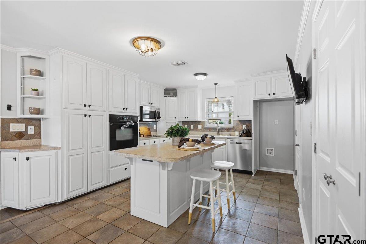 701 Georgia Street Lindale, TX 75771 - Photo 11 of 37 a kitchen with white cabinets and stainless steel appliances