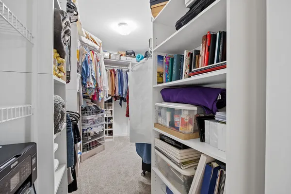 a view of walk in closet with clothes and shoes