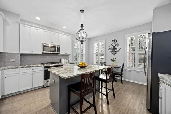 a kitchen that has a table chairs stainless steel appliances and cabinets
