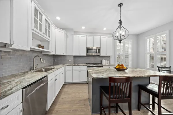 a kitchen with stainless steel appliances granite countertop a sink a stove center island and chairs