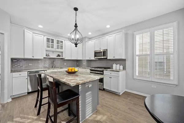 a kitchen with stainless steel appliances granite countertop a stove top oven a refrigerator a sink and white cabinets