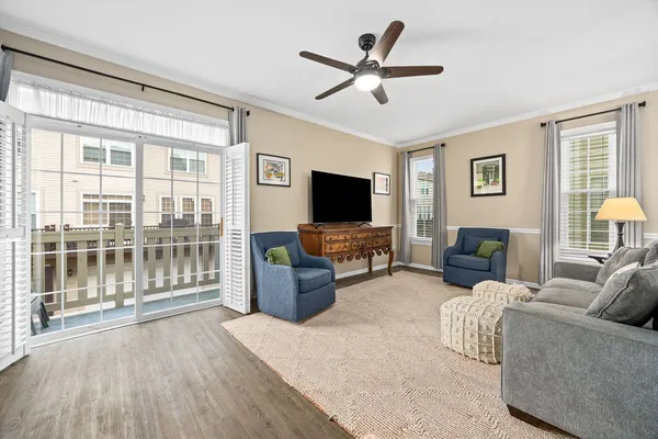 a living room with furniture a ceiling fan a flat screen tv and a large window