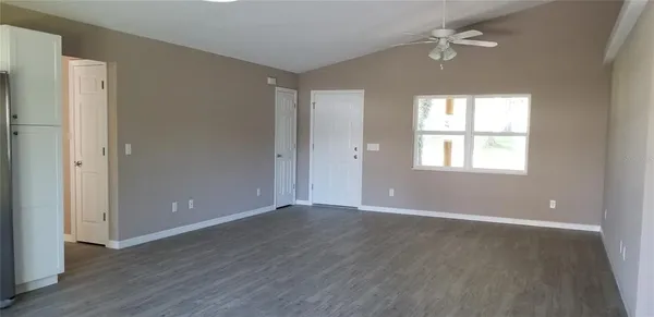 a view of an empty room with a window and wooden floor