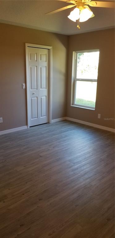 326 Clark Street Inverness, FL 34452 - Photo 9 of 19 an empty room with wooden floor chandelier fan and windows
