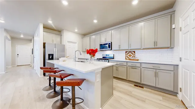 a kitchen with stainless steel appliances granite countertop a sink a stove a refrigerator cabinets and chairs