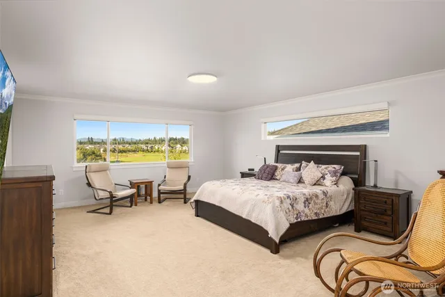 a bedroom with a bed chair and two windows