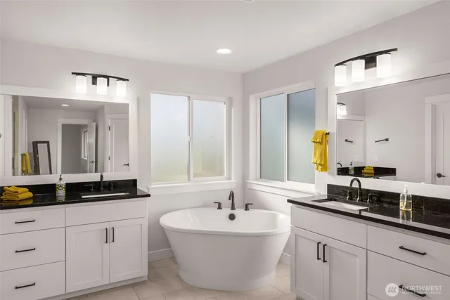 a bathroom with a double vanity sink a mirror and a bathtub