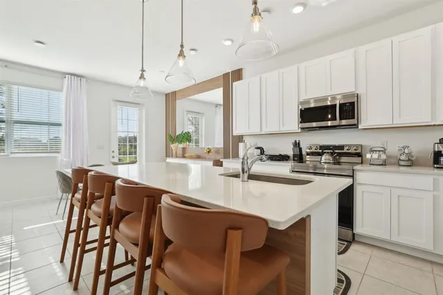 a kitchen with stainless steel appliances granite countertop a stove a sink dishwasher a microwave oven with a dining table and chairs