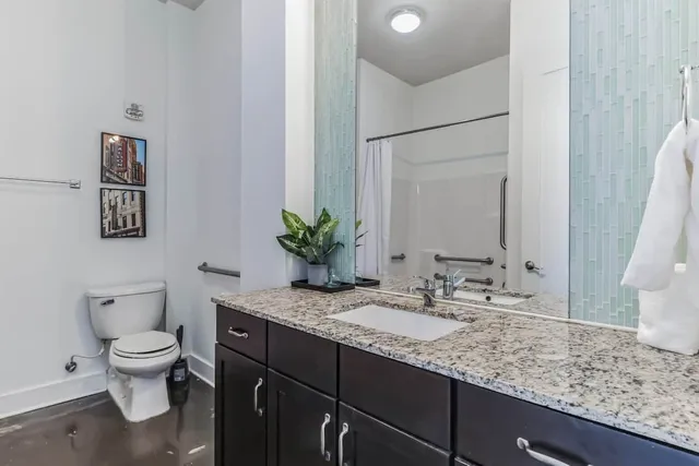 a bathroom with a granite countertop sink a toilet and bathtub