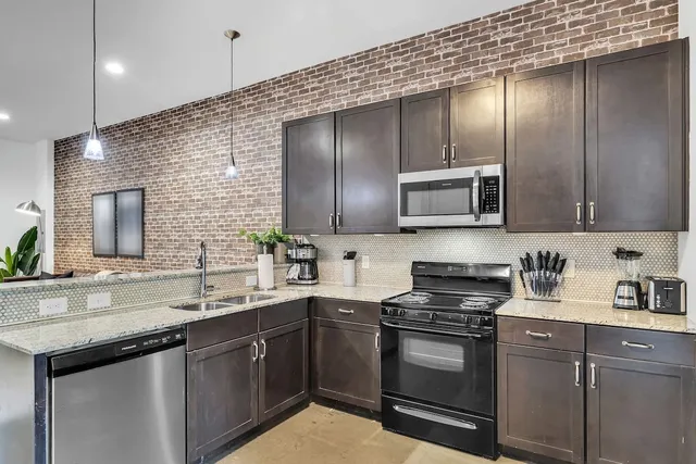 a kitchen with stainless steel appliances granite countertop a sink and a refrigerator