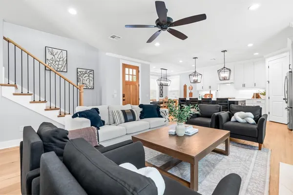 a living room with furniture a clock and a view of kitchen