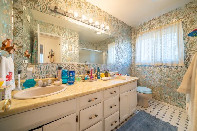 a bathroom with a double vanity sink toilet and a mirror