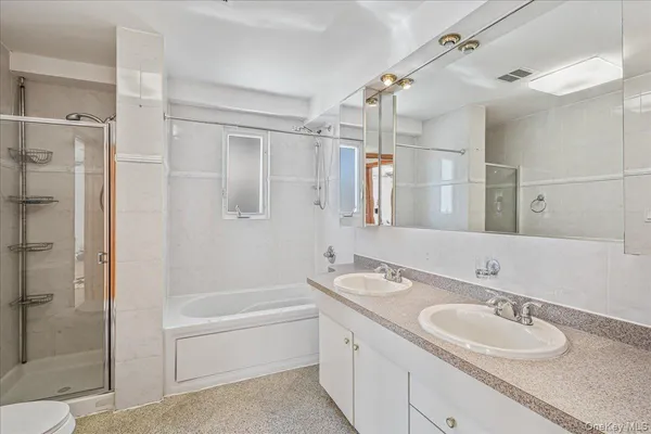 a bathroom with a granite countertop double vanity sink a mirror and a bathtub