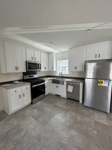 a kitchen with stainless steel appliances granite countertop a refrigerator sink and white cabinets