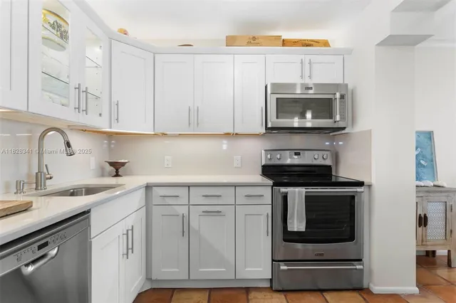 a kitchen with white cabinets and stainless steel appliances