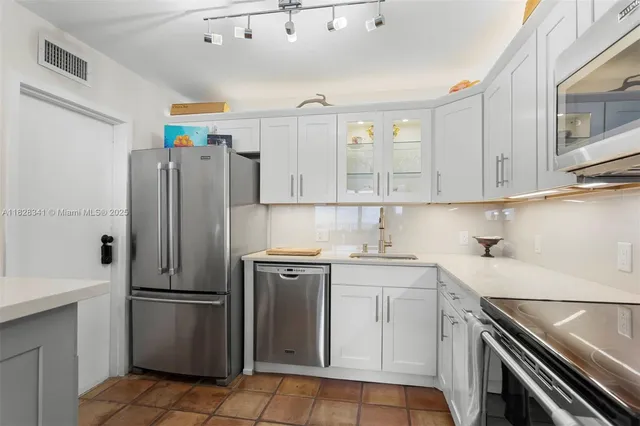a kitchen with a refrigerator sink and cabinets