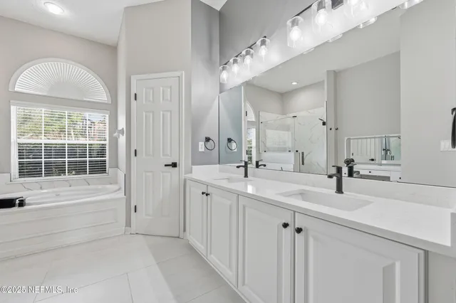 a spacious bathroom with a tub sink and mirror