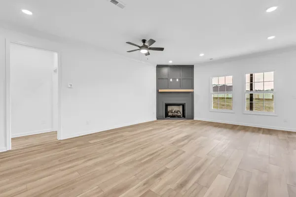 an empty room with wooden floor fireplace and a window