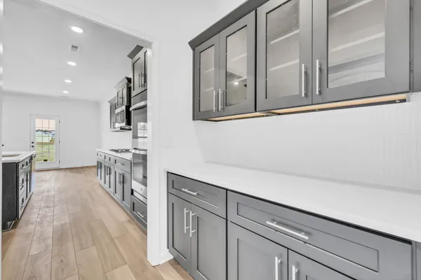 a hallway with white cabinets and wooden floor