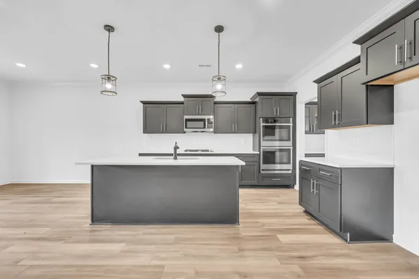 a large kitchen with stainless steel appliances wooden floor and a view of living room