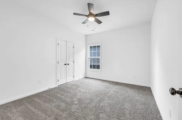 an empty room with a ceiling fan and a window