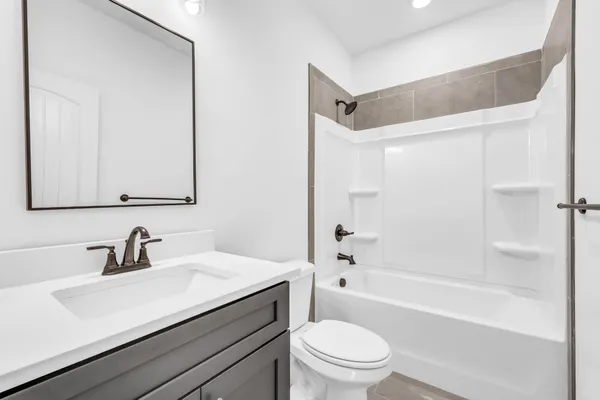 a bathroom with a sink a toilet a mirror a bathtub and shower