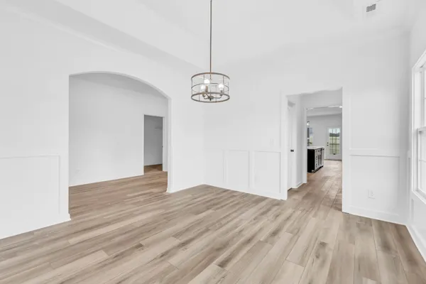 a view of a hallway with wooden floor and a chandelier