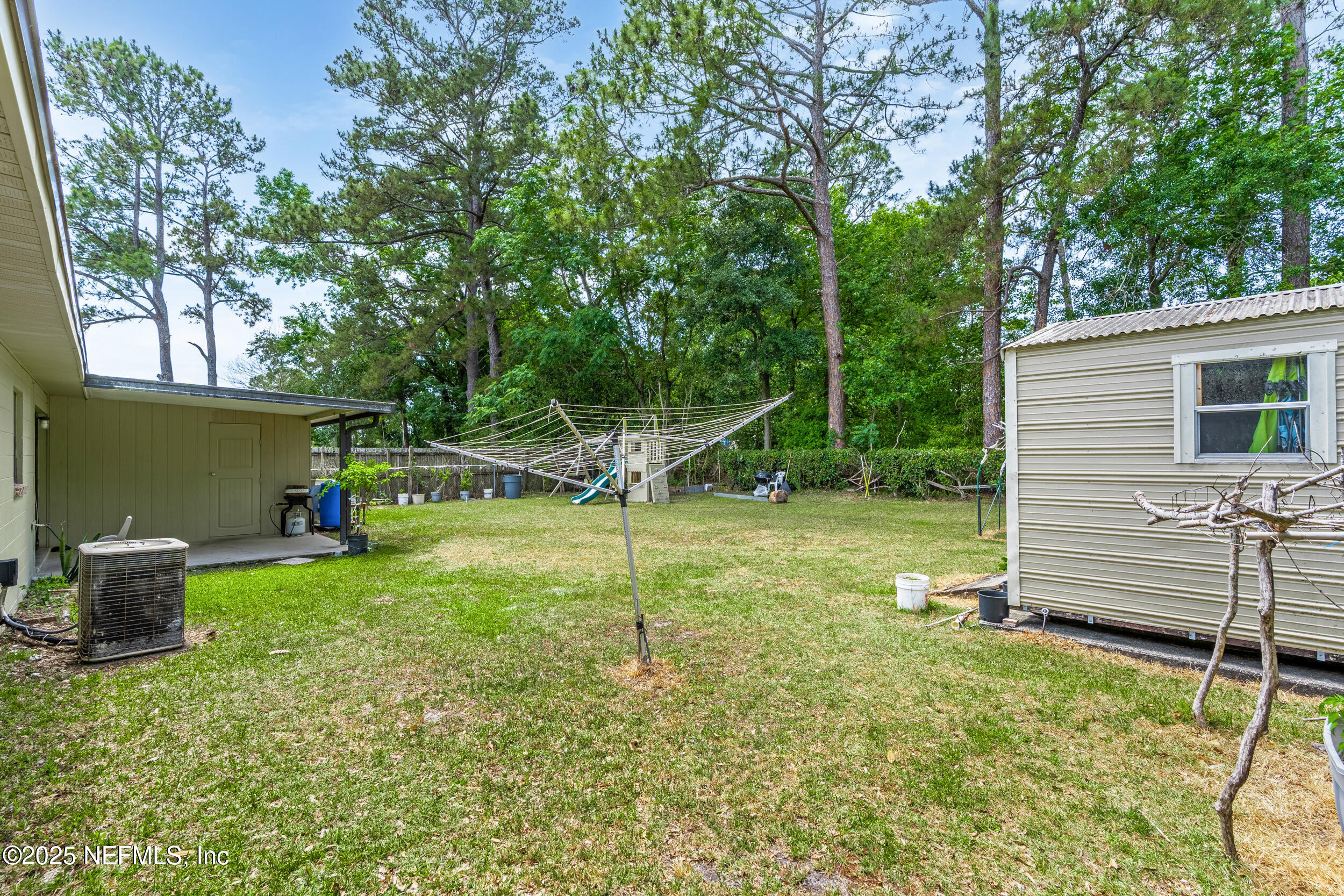 2826 Sam Road Jacksonville, FL 32216 - Photo 33 of 34 a view of a backyard with a slide trees and wooden fence