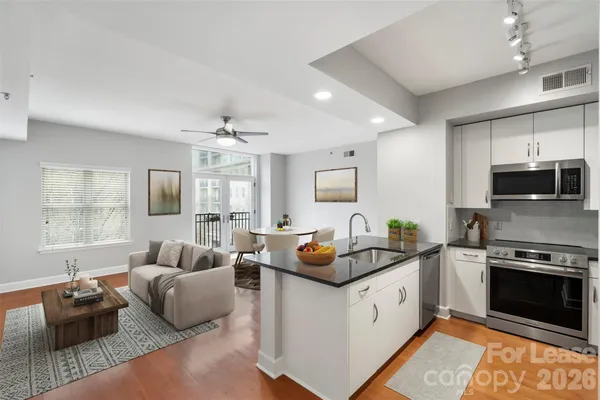 a white kitchen with stainless steel appliances granite countertop a stove and a sink
